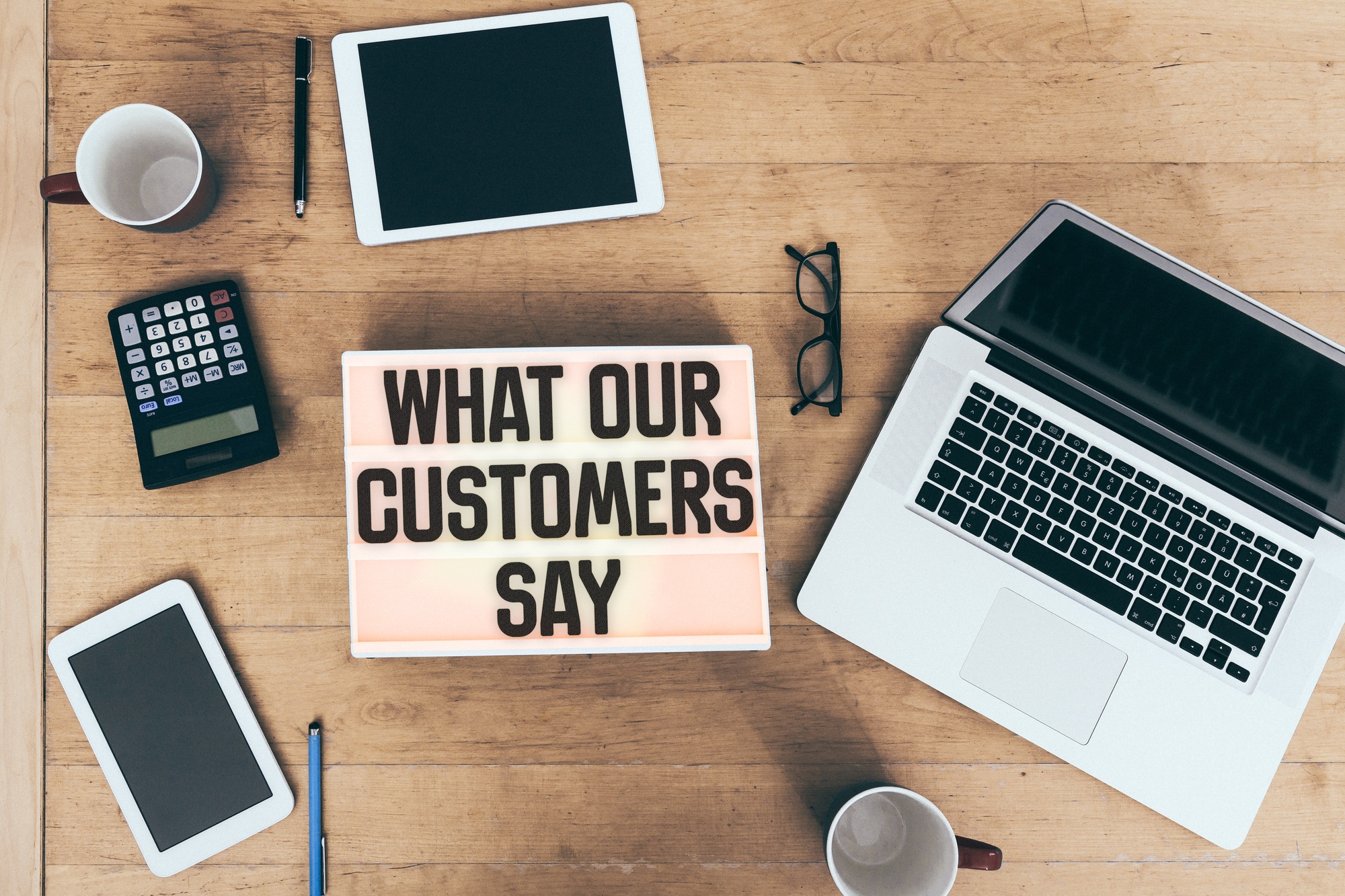 Customer testimonial message on light box at office desk with connected electronic devices