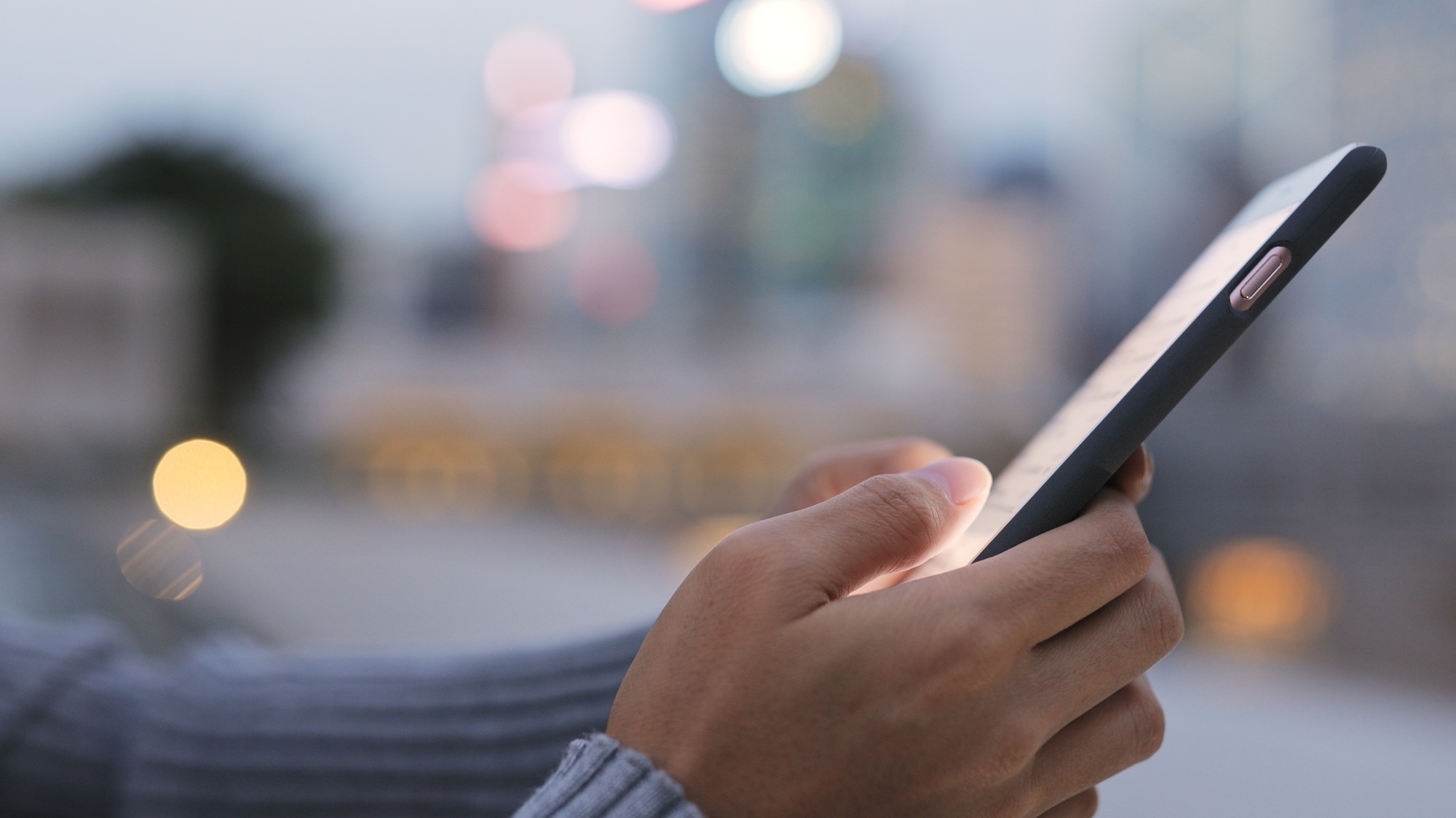 Responsive mobile phone with app interface on the screen, modern technology, person holding device, urban background, blurred cityscape, digital communication, smartphone technology, Brisbane, Sydney, Melbourne, Australia.